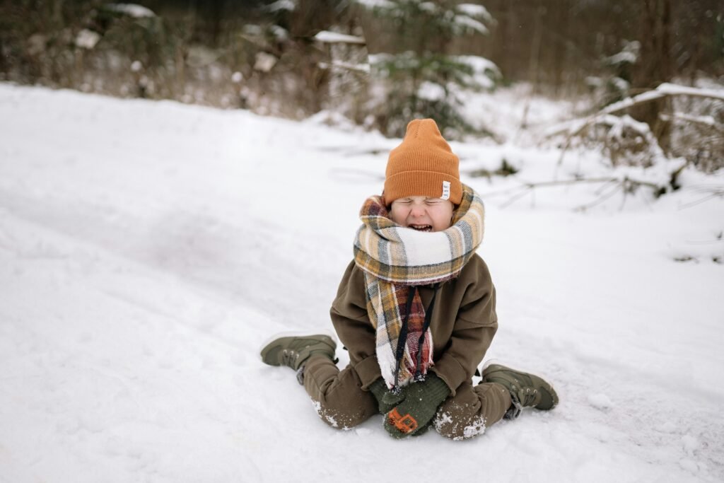Toddler having a tantrum Toddler sitting in the snow with eyes closed and an expressive face, wrapped in a warm scarf and winter clothes, showing big emotions outdoors., tantrums