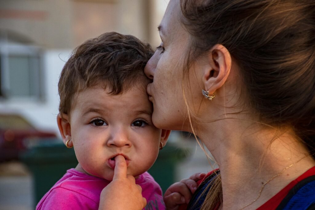 Gentle vs. snowplow parenting, a mother is kissing her toddlers forehead